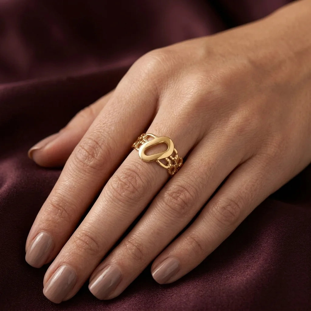 Gold ring on a hand with a maroon fabric background
