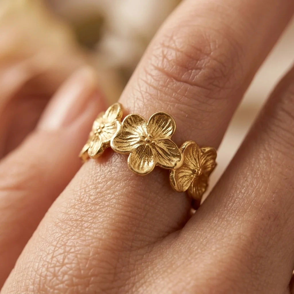 Gold floral ring on a person's finger with a blurred background