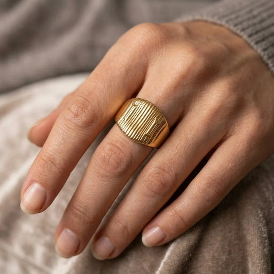 Gold ring on a finger with a neutral background