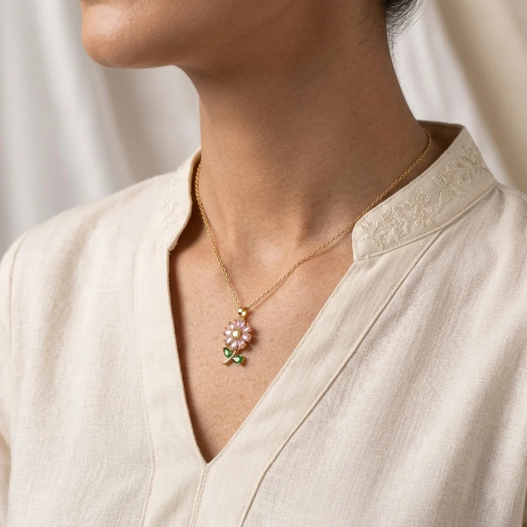 Necklace with a floral pendant worn by a person in a light-colored outfit.