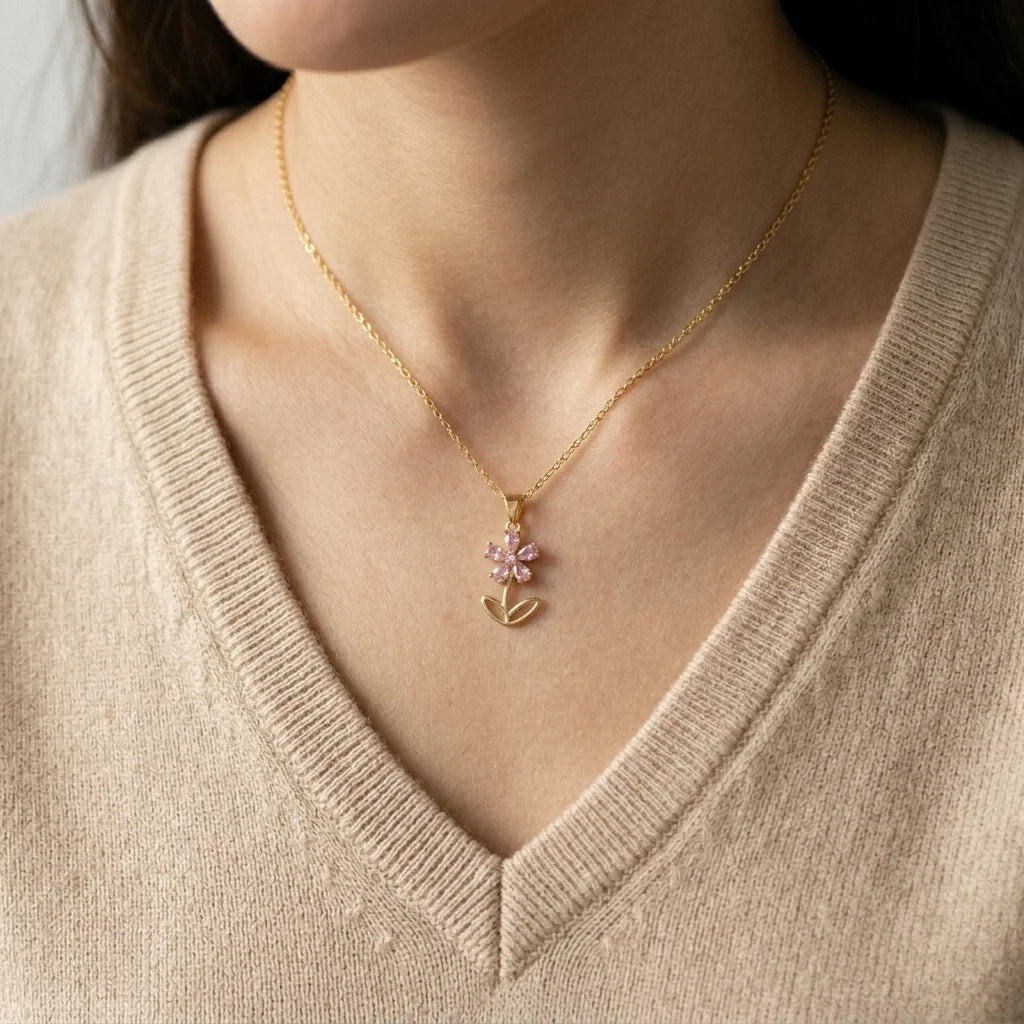 Necklace with a floral pendant worn by a person in a beige sweater.