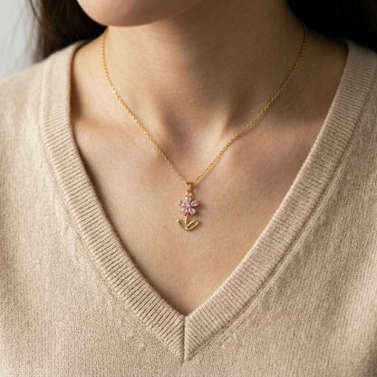 Necklace with a floral pendant worn by a person in a beige sweater.