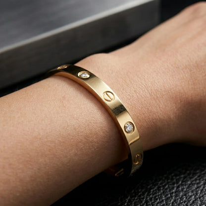Gold bracelet with diamond accents on a wrist against a dark background