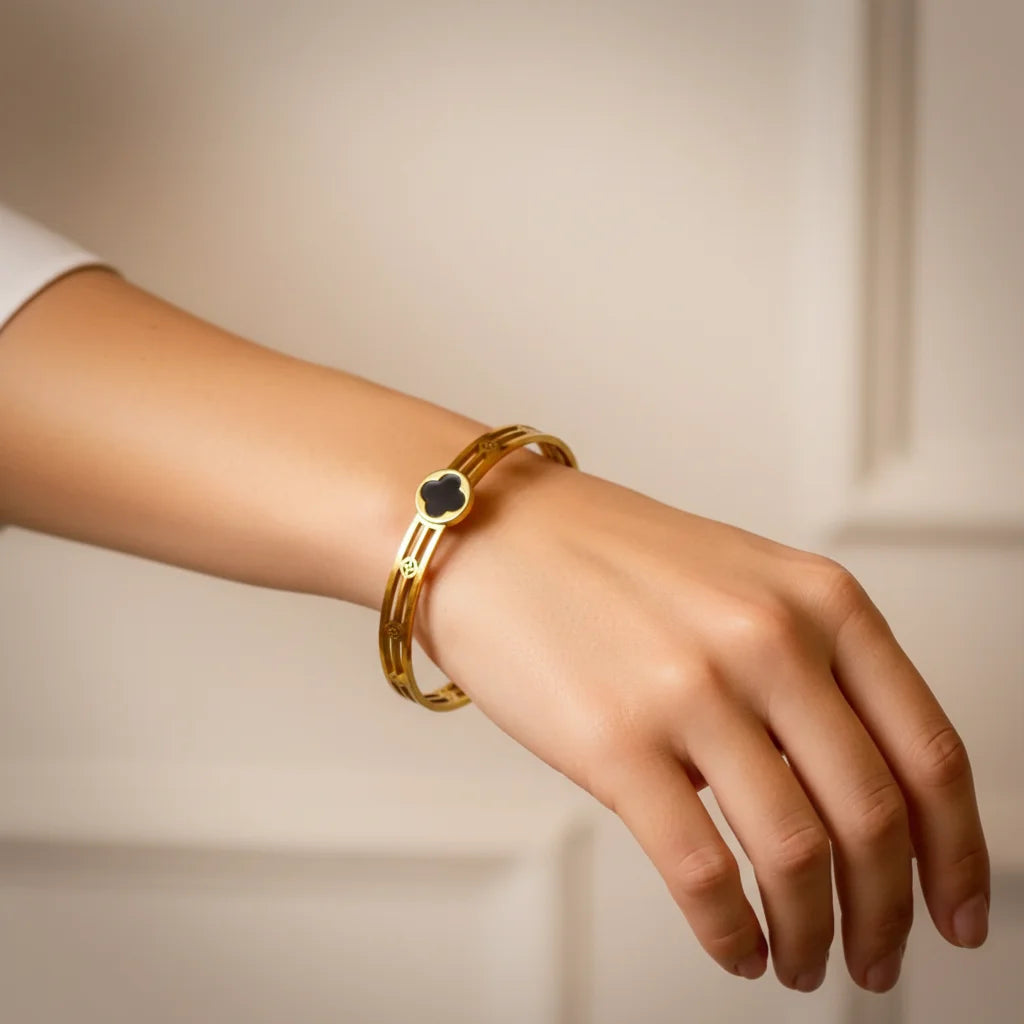 Gold bracelet on a wrist against a neutral background