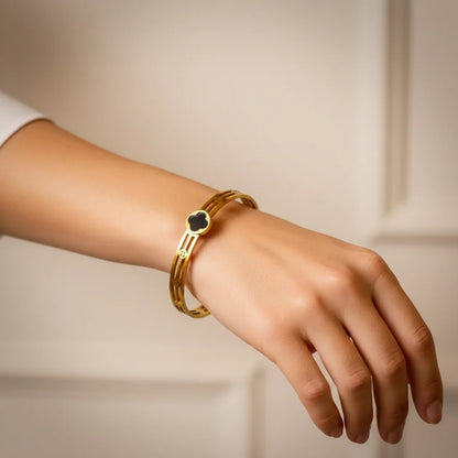 Gold bracelet on a wrist against a neutral background