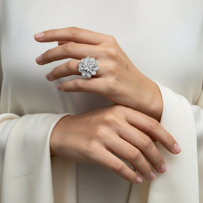 Hand wearing a silver floral ring against a white background