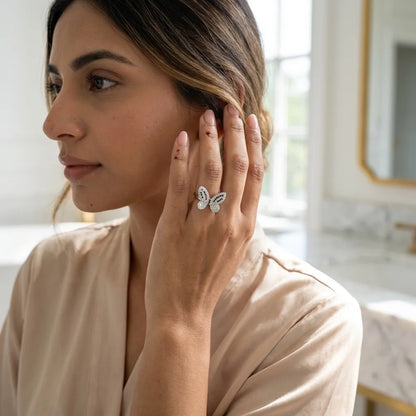 Woman wearing a butterfly-shaped earring in a softly lit room.
