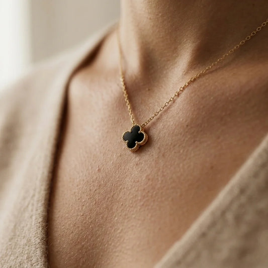 Gold necklace with a clover-shaped pendant on a person's neck