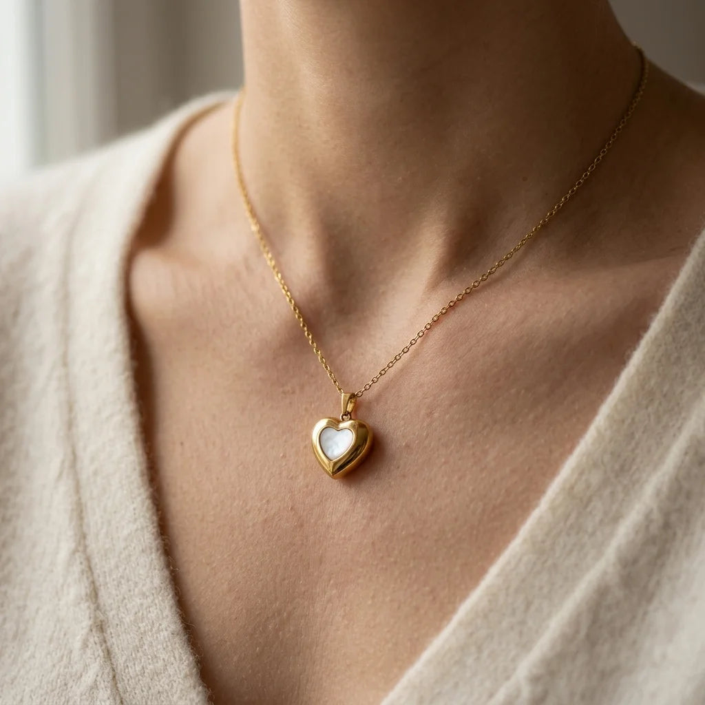 Gold necklace with a heart-shaped pendant worn by a person in a neutral setting