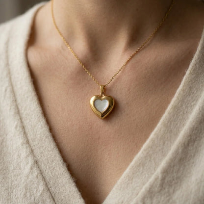 Gold heart-shaped pendant necklace on a person wearing a light-colored garment.