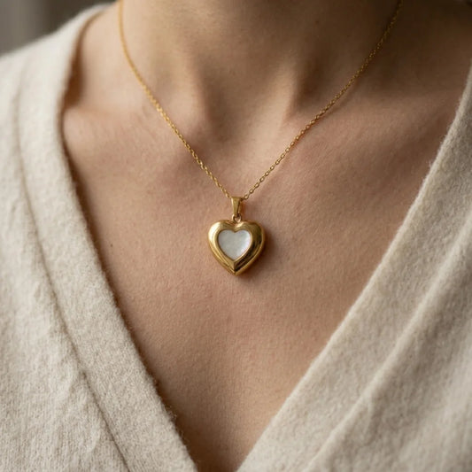 Gold heart-shaped pendant necklace on a person wearing a light-colored garment.