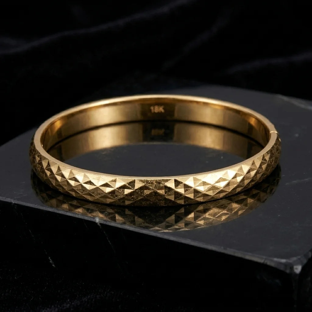 Gold bracelet with textured design on a black background
