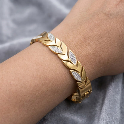 Gold bracelet with diamond accents on a wrist against a gray fabric background