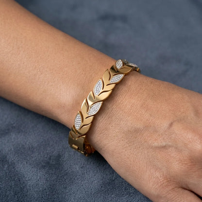 Gold bracelet with diamond accents on a wrist against a gray background