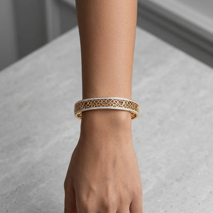 Hand wearing a gold bracelet on a neutral background