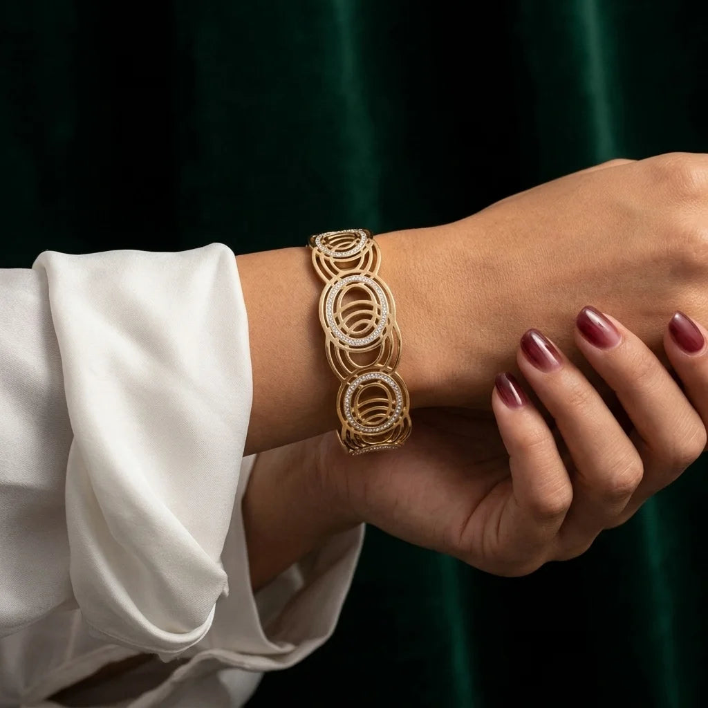 Gold bracelet on a wrist with a white sleeve against a dark background