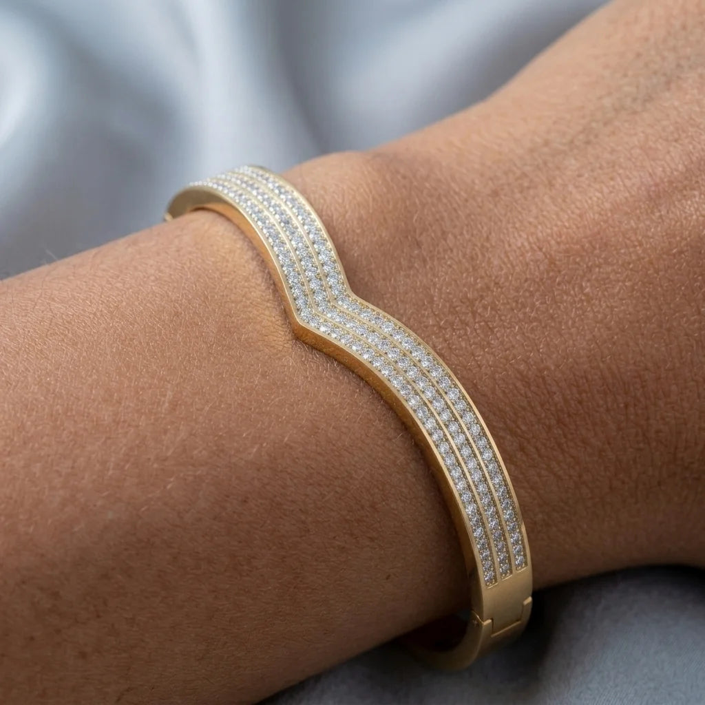 Gold bracelet with clear stones on a wrist against a neutral background