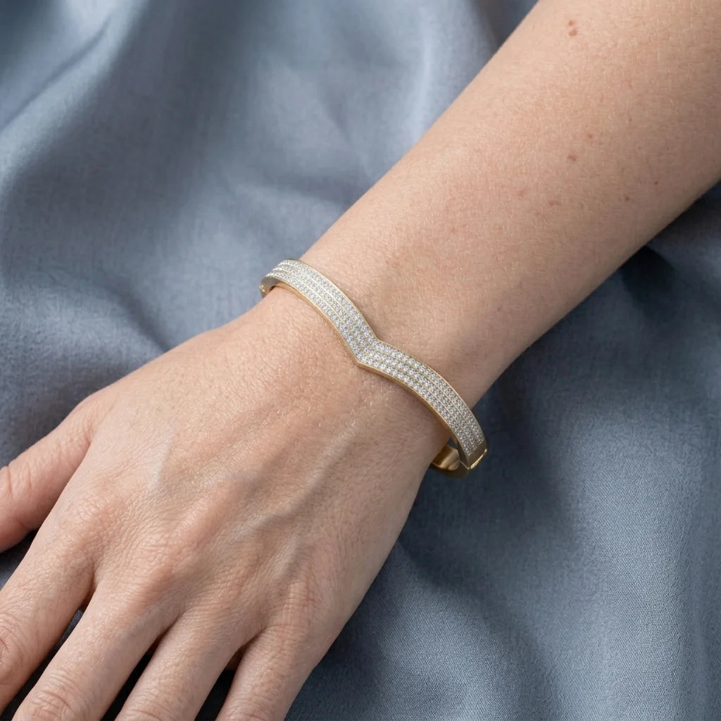 Gold bracelet on a wrist against a blue fabric background