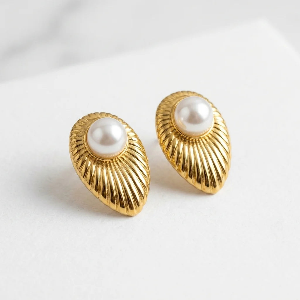 Gold earrings with pearl centers on a light gray background