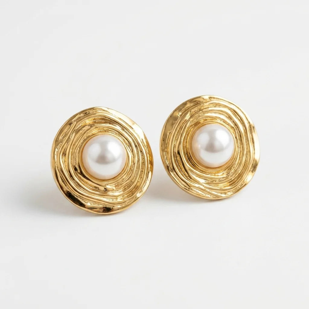 Gold earrings with pearl centers on a light gray background