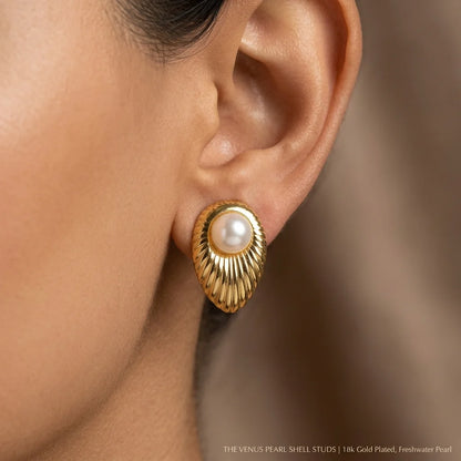 Gold earring with pearl detail worn by a person, on a blurred background