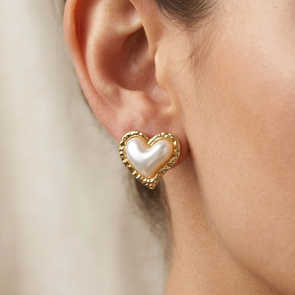 Heart-shaped earring worn by a person with a neutral background