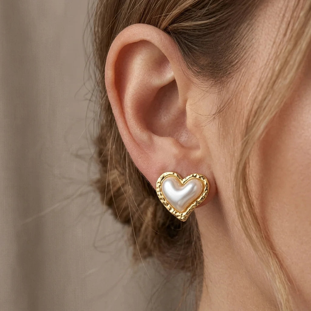 Heart-shaped earring with pearl center worn by a person