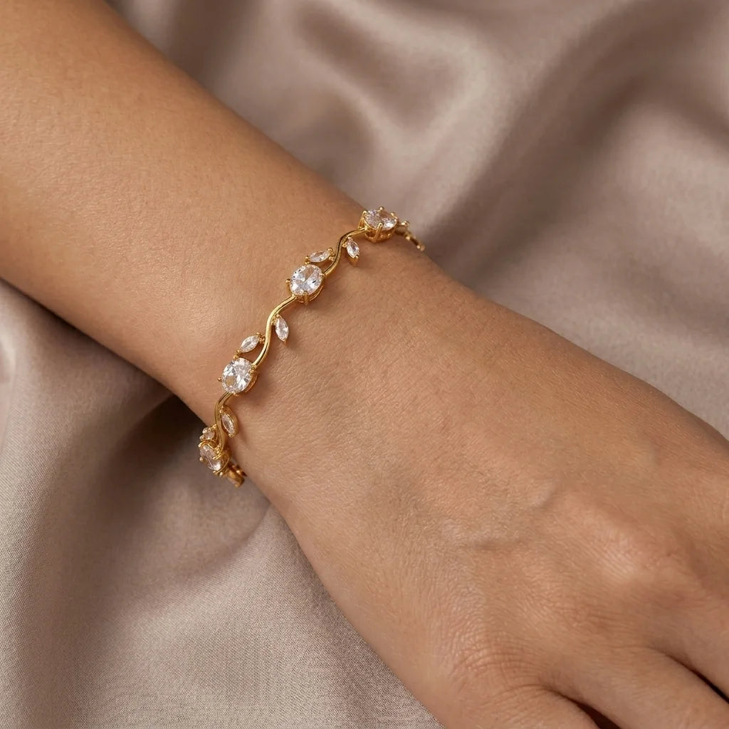 Gold bracelet with crystals on a wrist against a beige fabric background