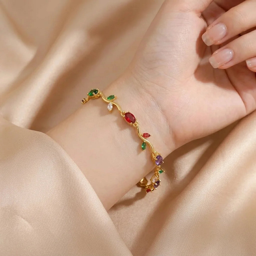 Gold bracelet with colorful stones on a hand against a beige fabric background