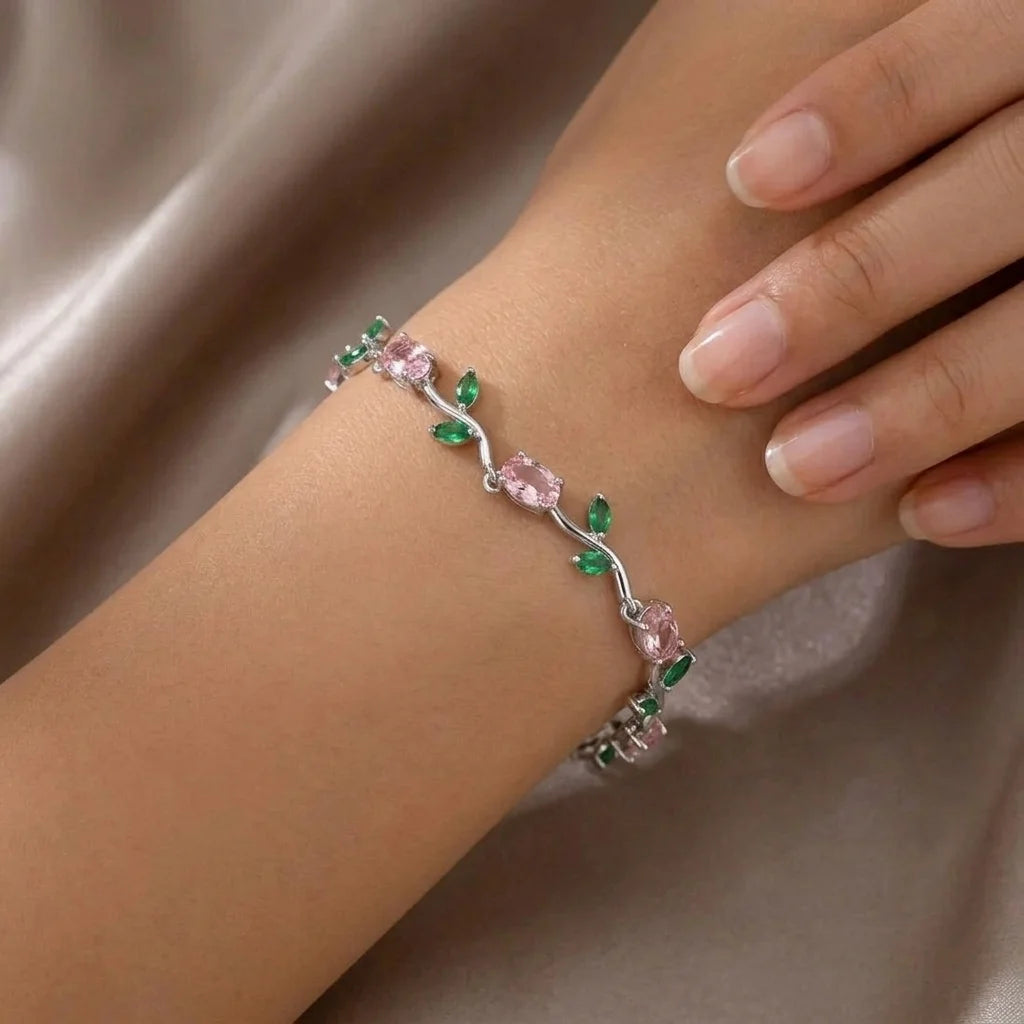Bracelet with pink and green gemstones on a wrist against a neutral background