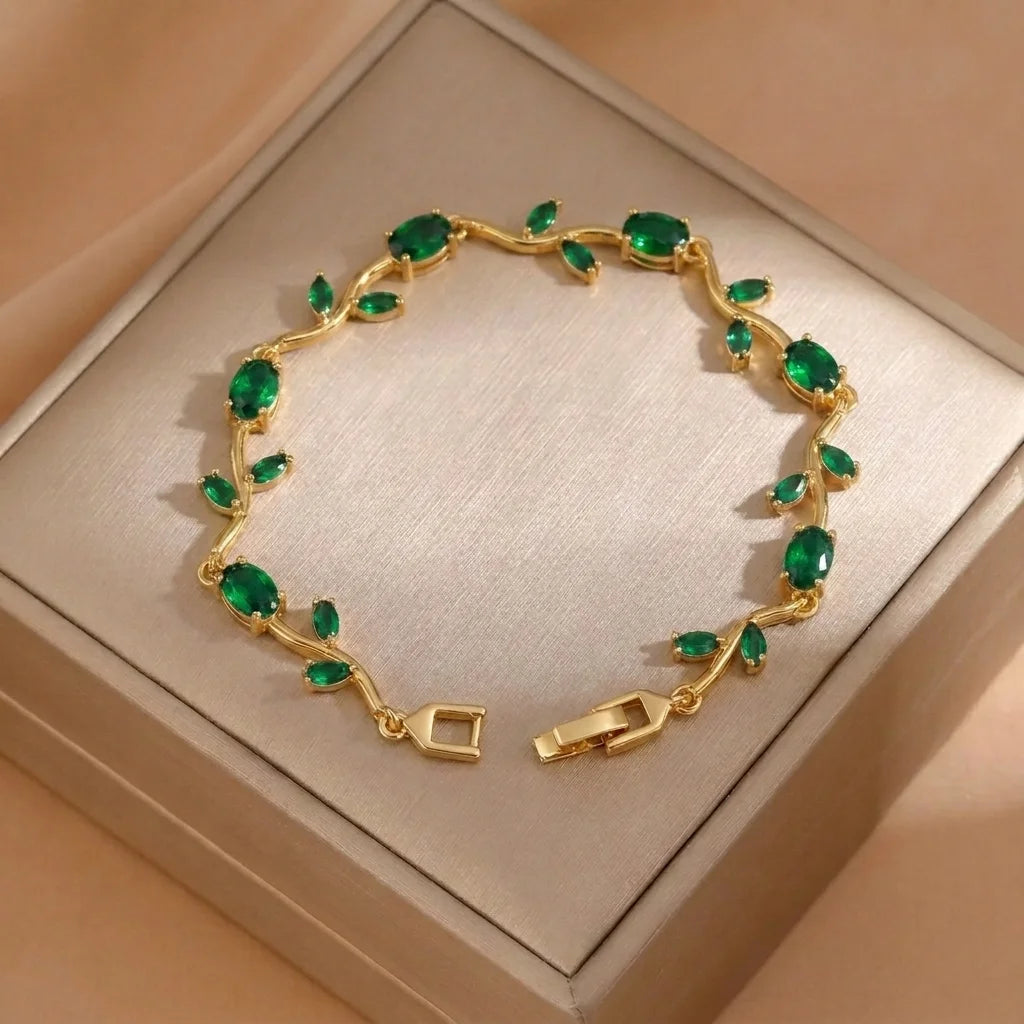 Gold bracelet with green gemstones on a beige box