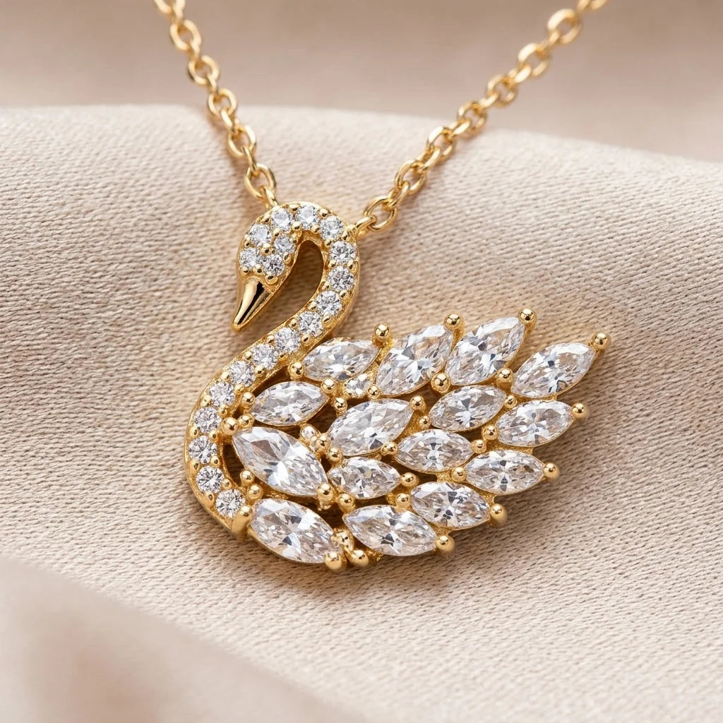 Gold swan-shaped necklace with diamond accents on a beige fabric background