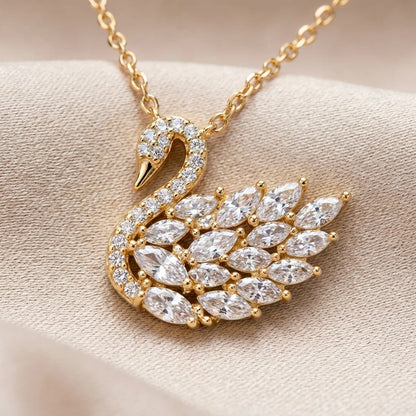 Gold swan-shaped necklace with diamond accents on a beige fabric background