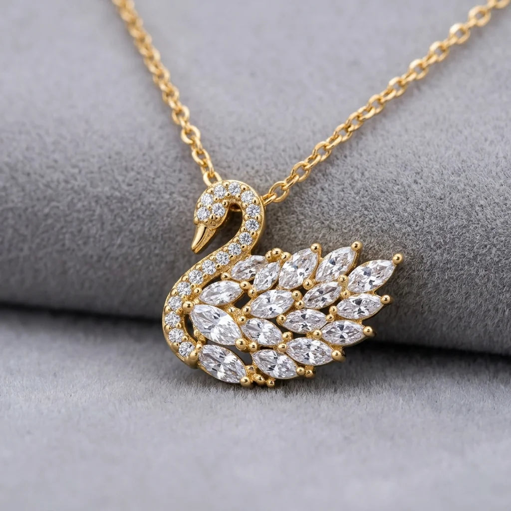 Gold swan-shaped necklace with diamond accents on a gray surface