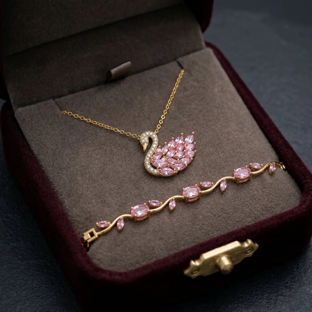 Gold jewelry set with pink gemstones in a brown jewelry box.