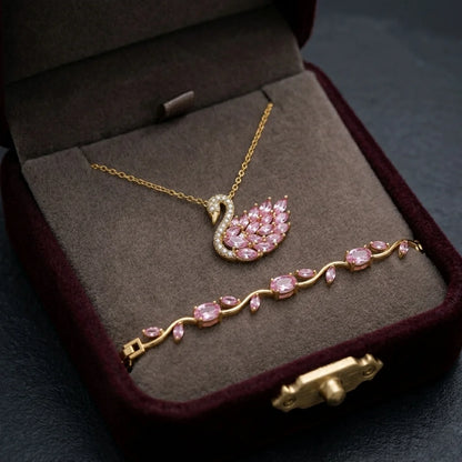 Gold jewelry set with pink gemstones in a brown jewelry box.