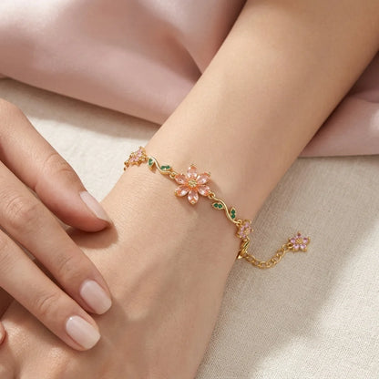Delicate gold bracelet with floral designs on a wrist against a soft background