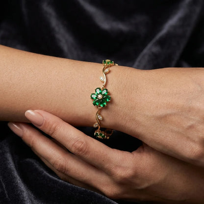 Gold bracelet with green gemstones on a wrist against a dark background