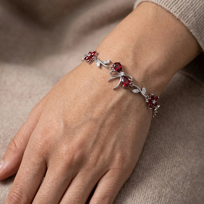 Silver bracelet with red gemstones on a wrist against a beige background
