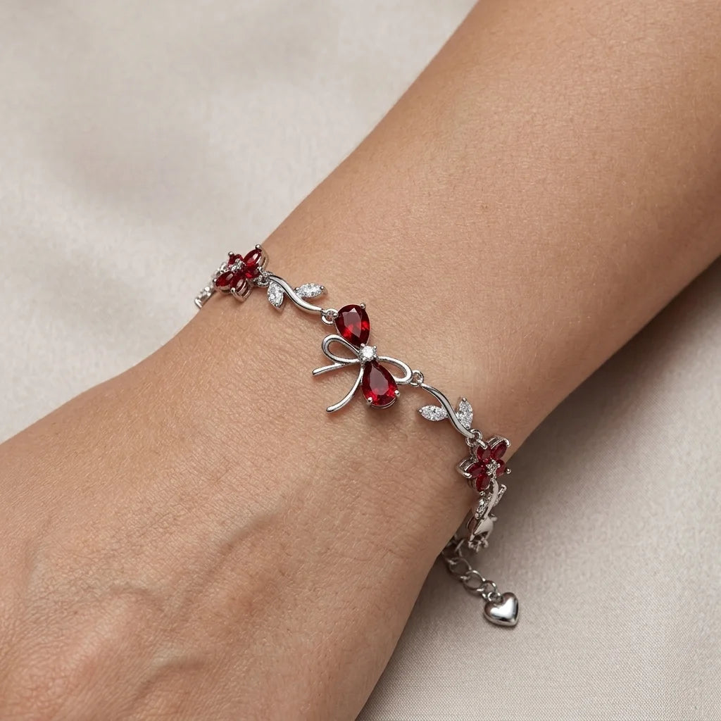 Silver bracelet with red gemstones on a wrist against a beige background