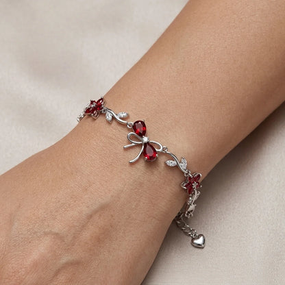 Silver bracelet with red gemstones on a wrist against a beige background