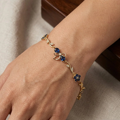 Gold bracelet with blue stones on a wrist against a neutral background