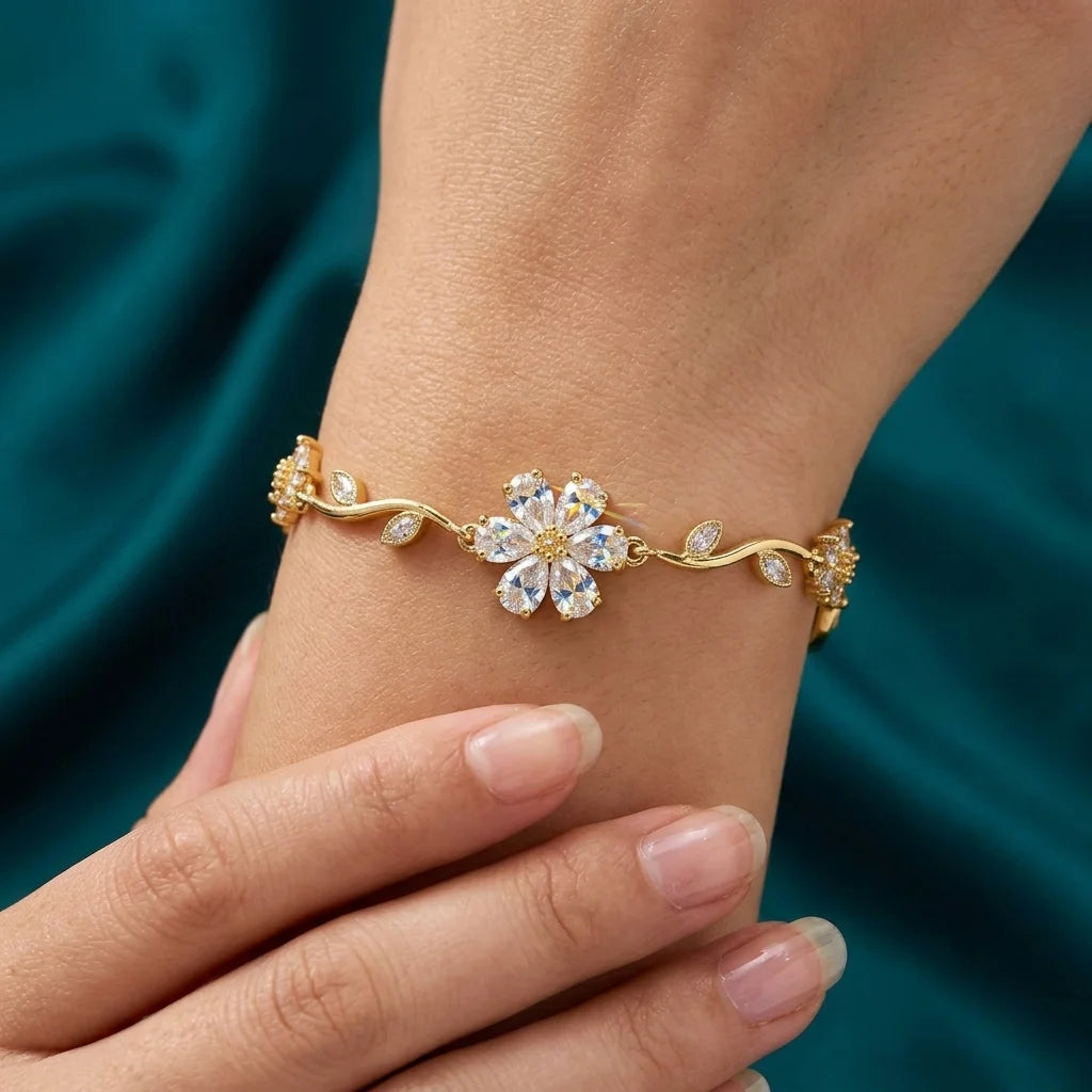 Gold bracelet with a floral design on a wrist against a teal fabric background
