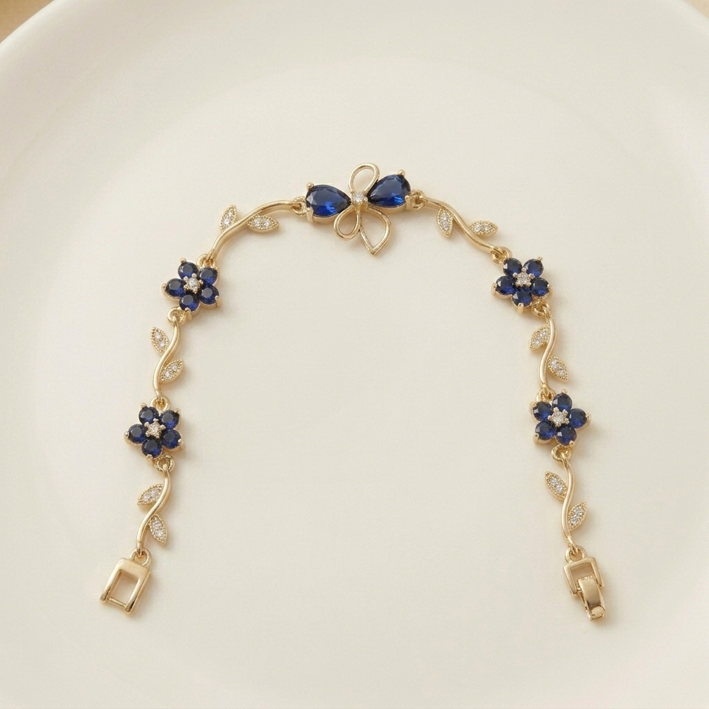 Gold bracelet with blue floral charms on a white plate