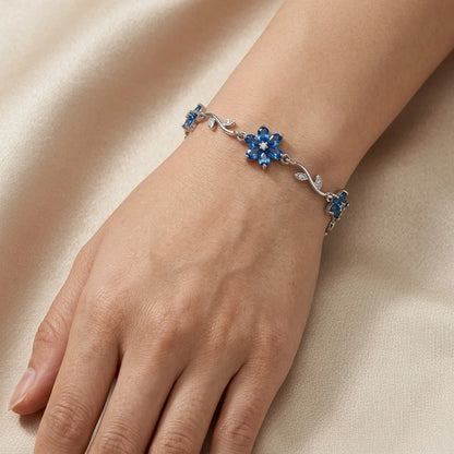 Silver bracelet with blue gemstones on a wrist against a beige background