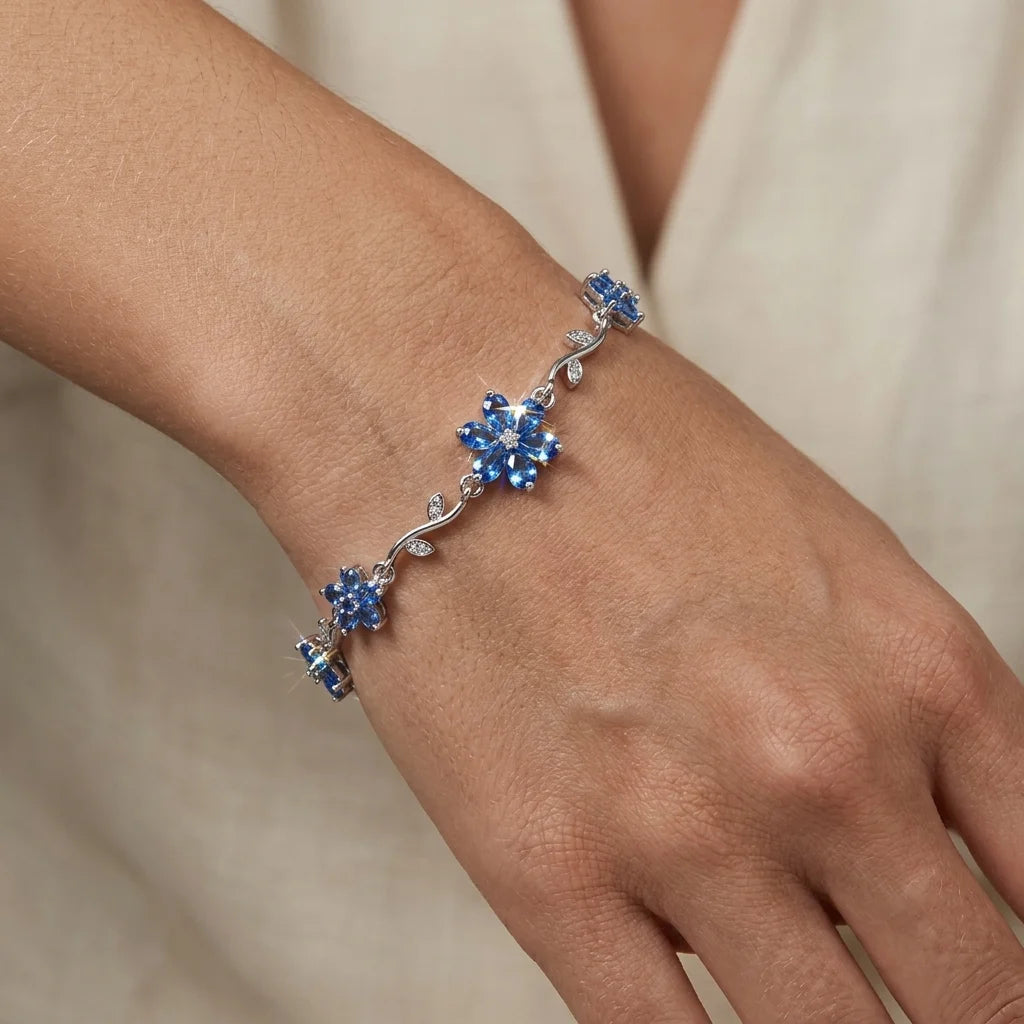 Silver bracelet with blue stones on a wrist against a neutral background