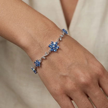 Silver bracelet with blue stones on a wrist against a neutral background