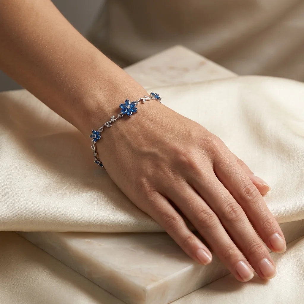 Hand wearing a bracelet with blue stones on a beige fabric background