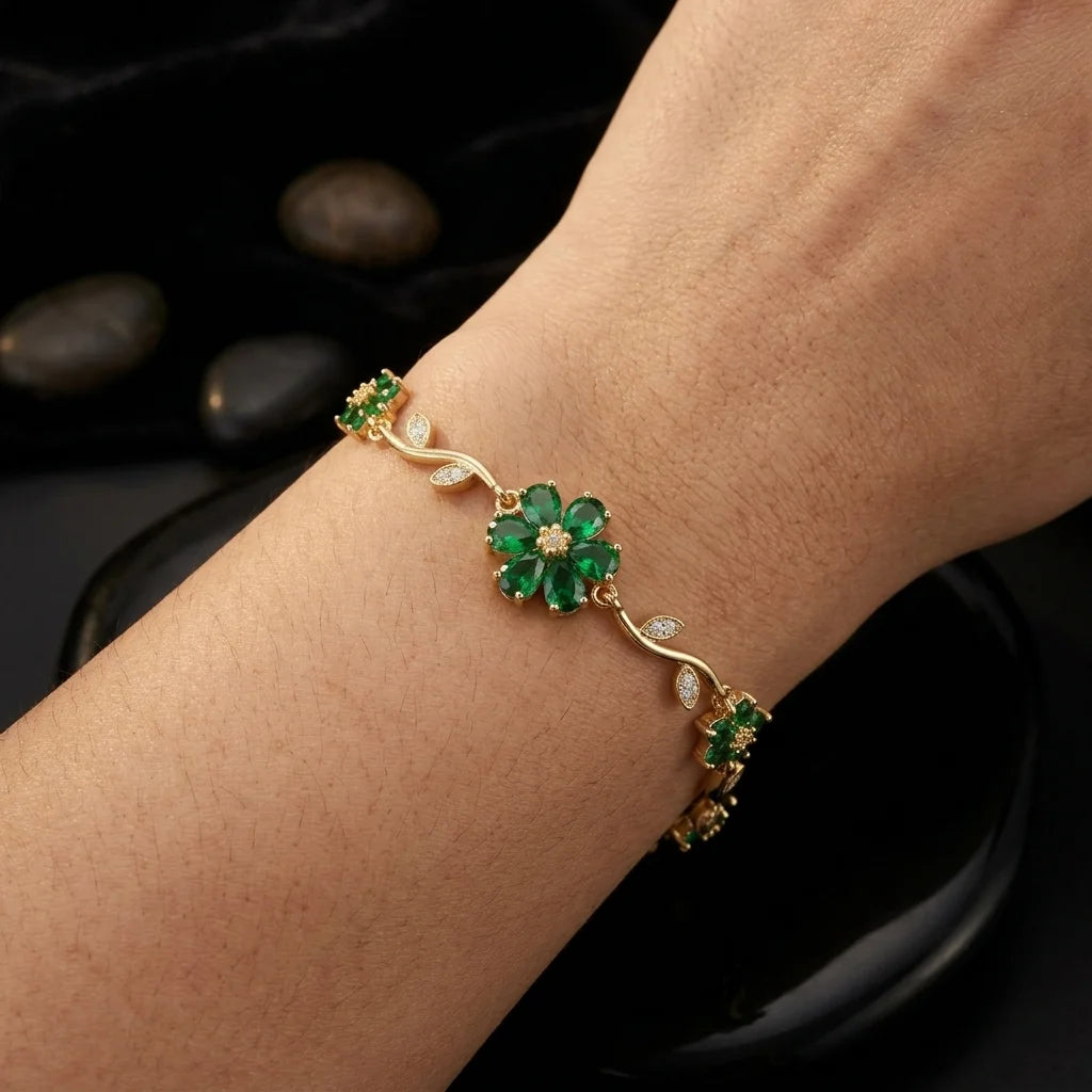 Gold bracelet with green gemstones on a wrist against a dark background
