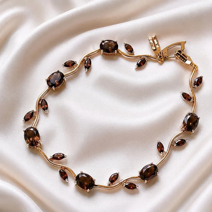 Gold bracelet with brown gemstones on a white fabric background